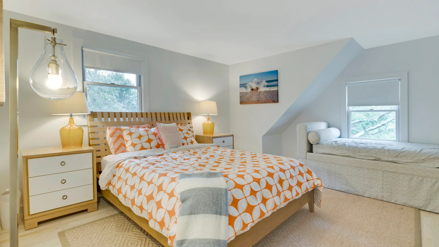 A bedroom with a bed covered in an orange-and-white patterned bedspread.