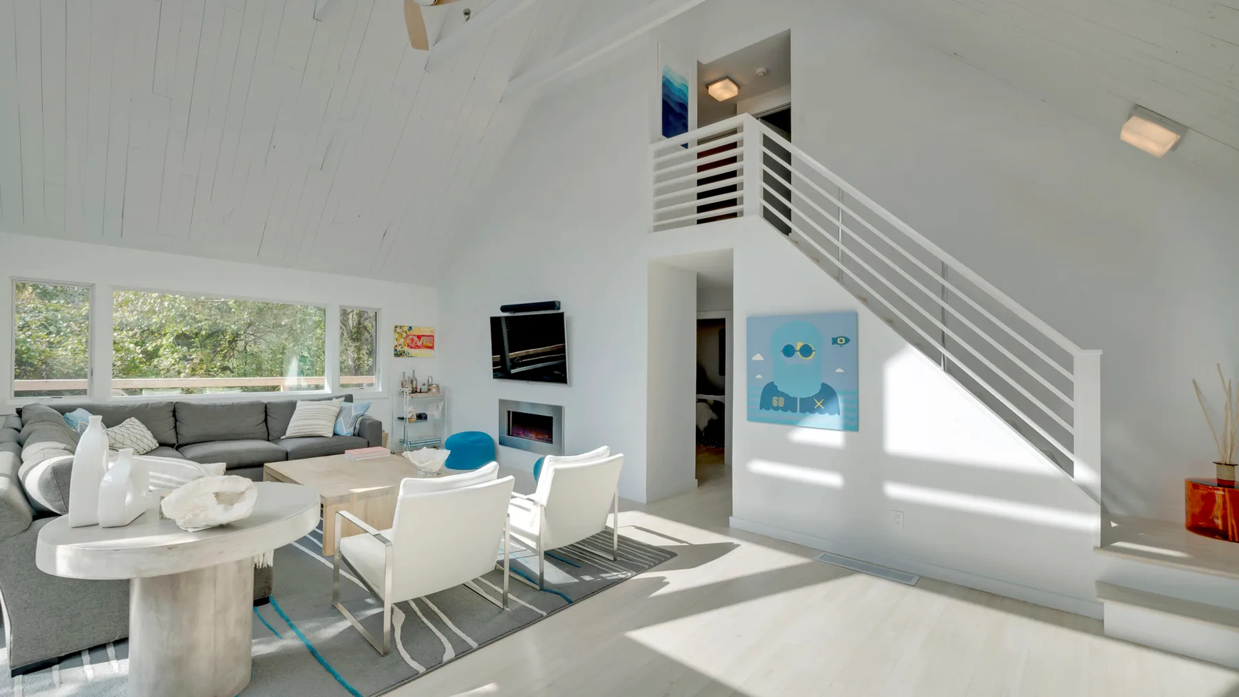 A bright open living area with seating, a dining table, and a staircase.