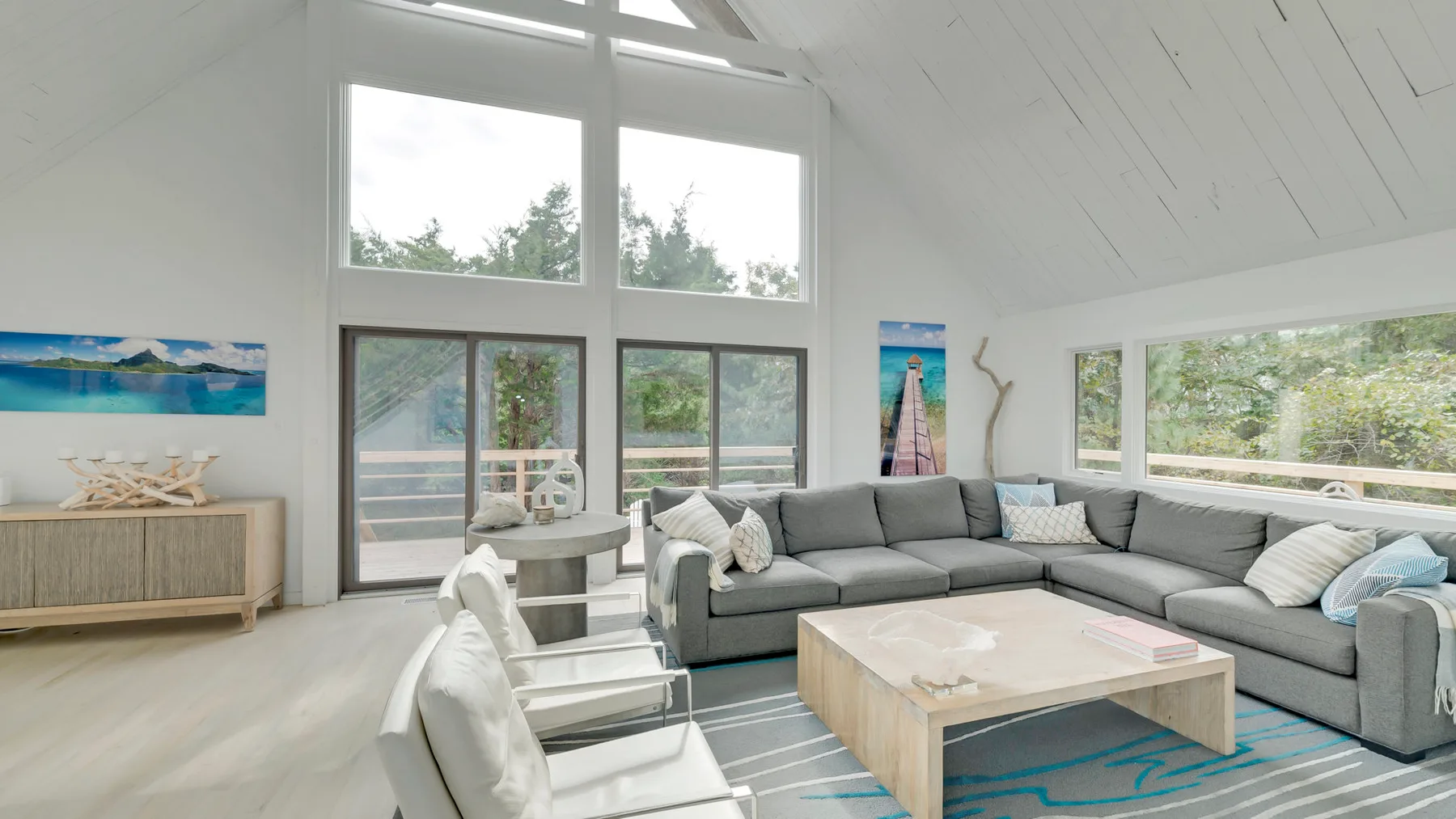 A bright living room with a gray sectional and large windows.