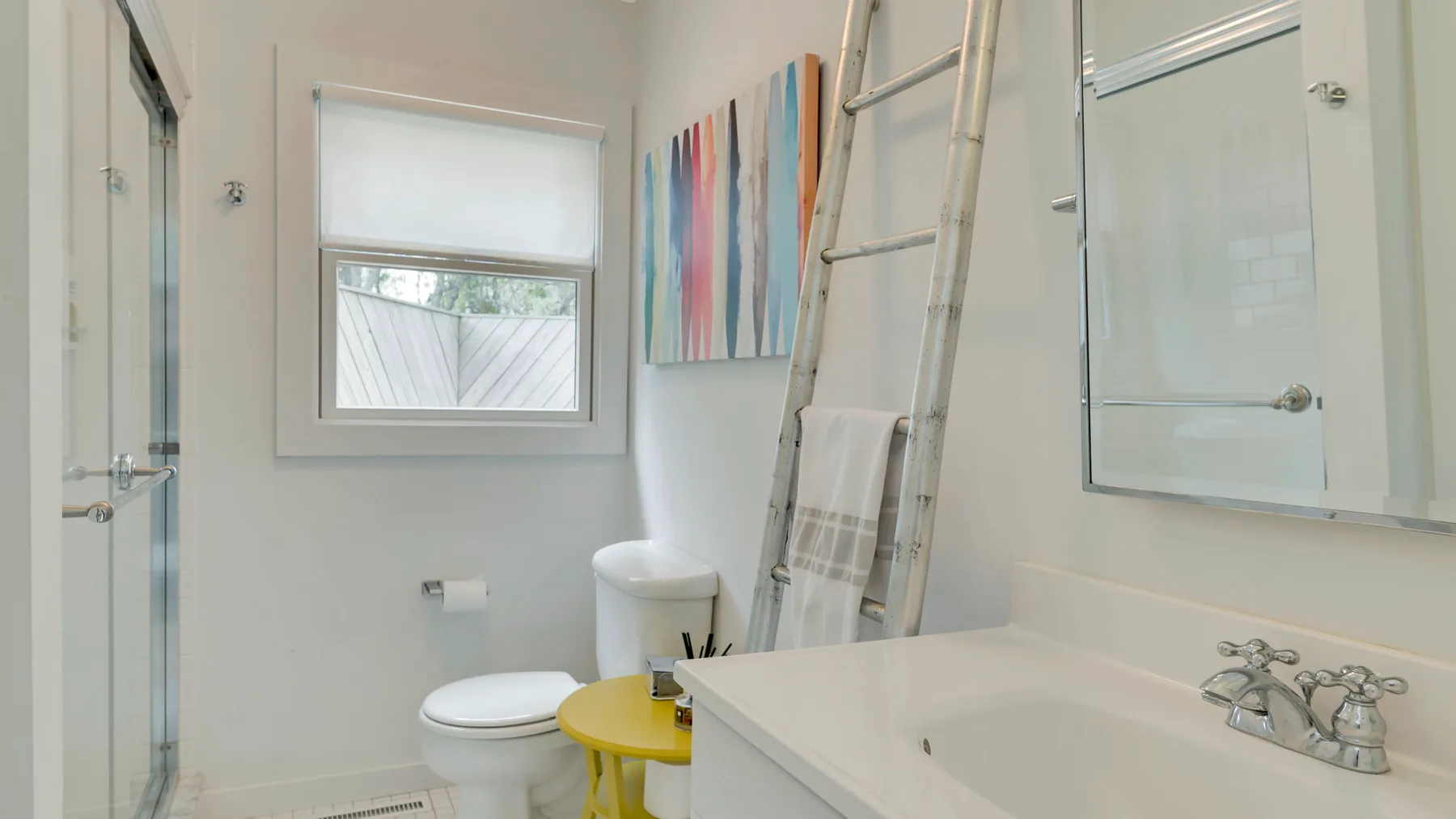 A bright bathroom with a bathtub, toilet, and window.