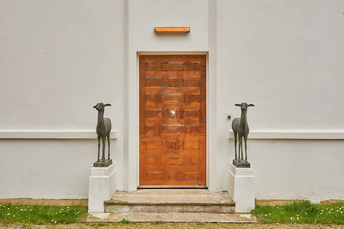 Una puerta de entrada de madera está flanqueada por dos esculturas de animales.