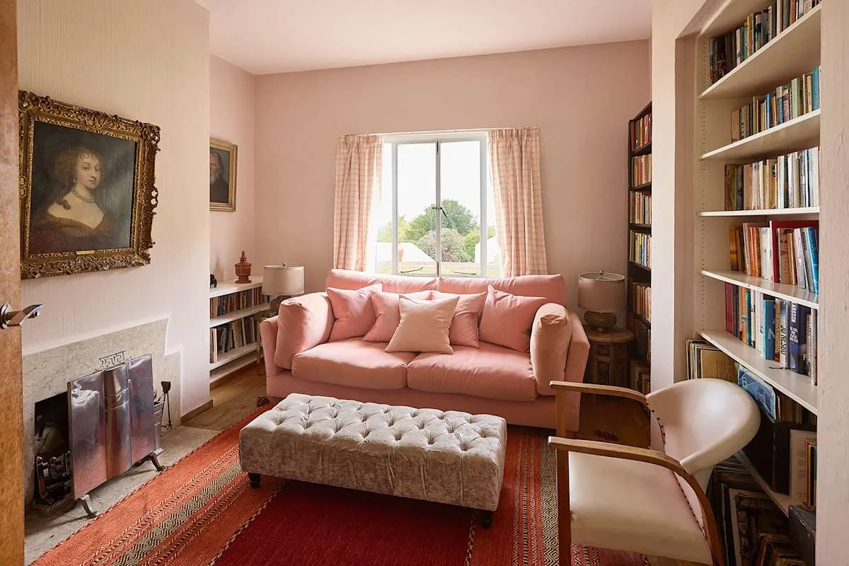 Una sala de estar con un sofá rosa y una ventana grande.