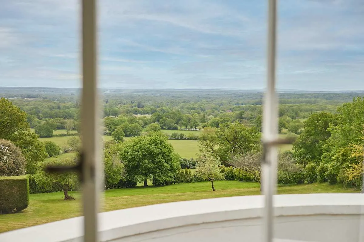 Un paisaje verde de campo se ve a través de una ventana.