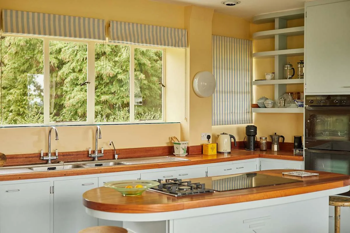 Una cocina luminosa con una amplia ventana sobre las encimeras y el fregadero.