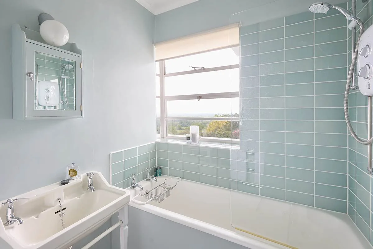 Un baño con bañera, lavabo y paredes revestidas de azulejos.