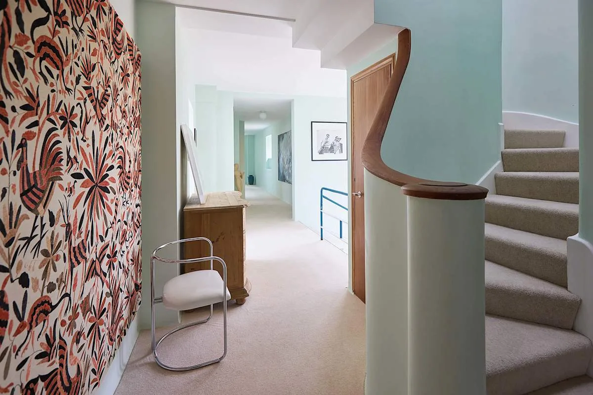 Un pasillo interior luminoso con una escalera y un revestimiento de pared estampado.