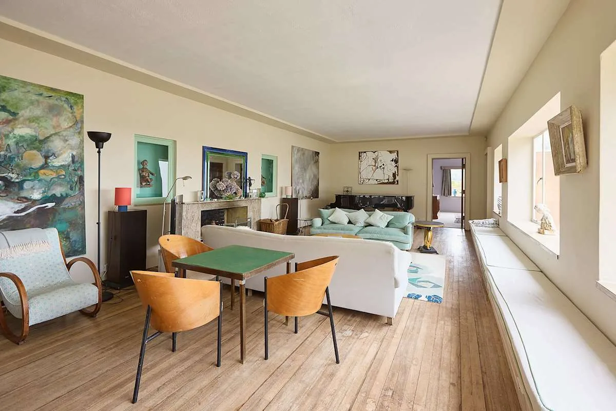 Sala de estar y comedor con asientos, una mesa de comedor y ventanales.