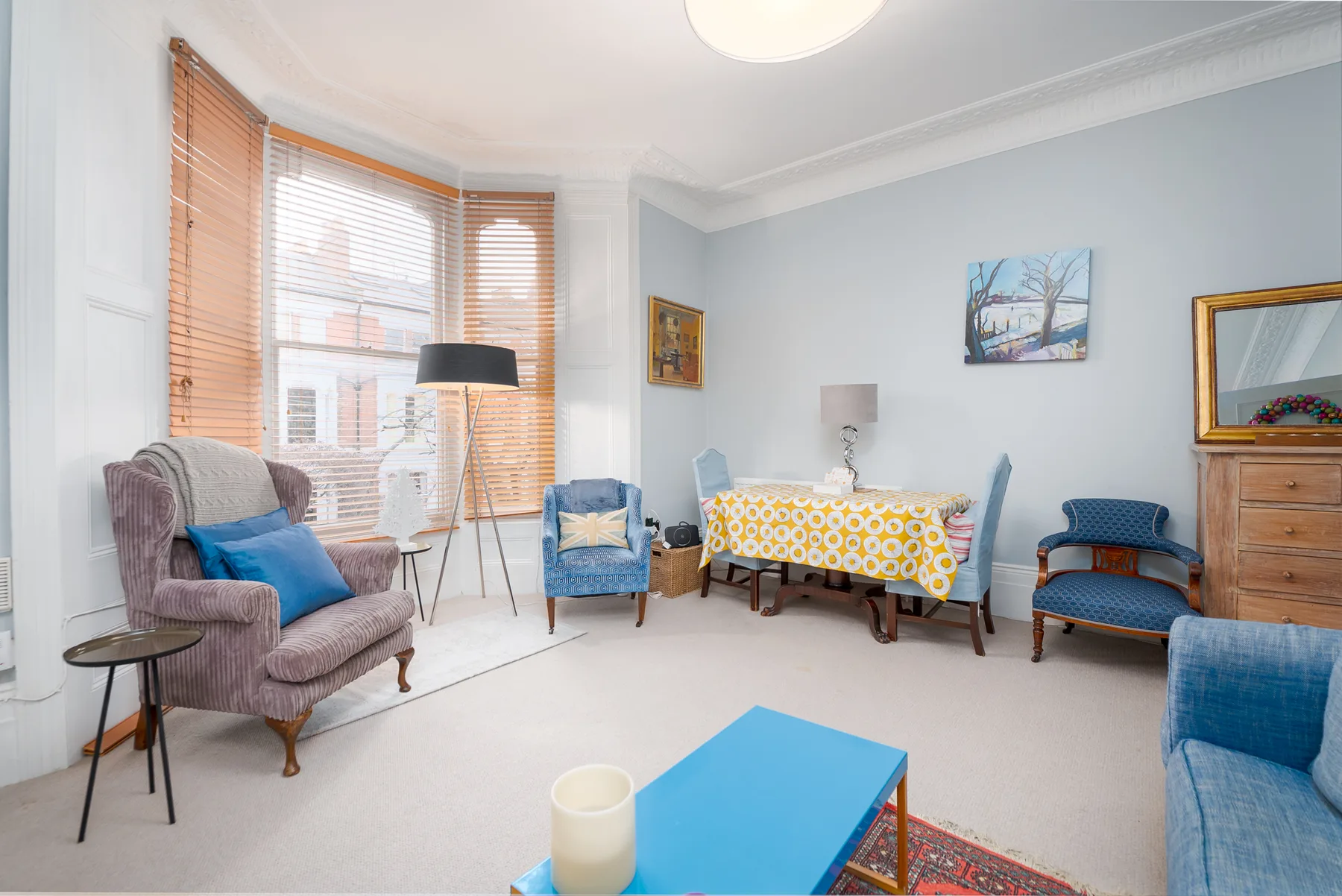 A bright living room with seating, a coffee table, and a dining table by the windows.