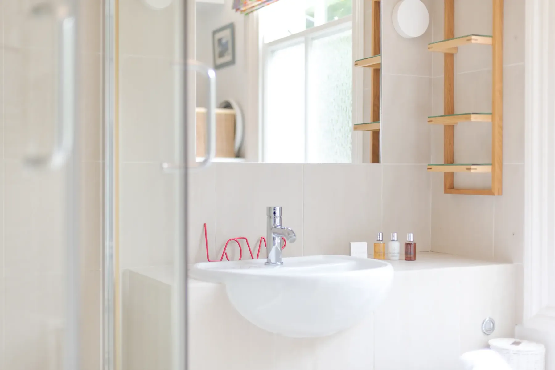 A bright bathroom with a sink and wall-mounted shelves.