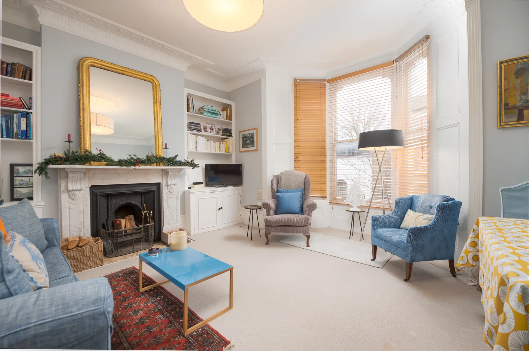 A bright living room with a fireplace, seating, and large windows.
