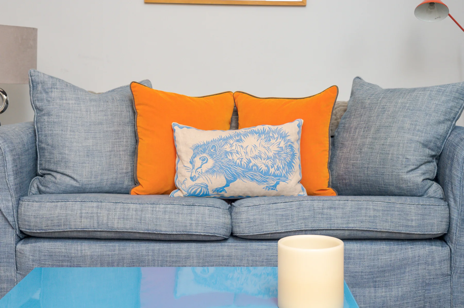 A living room seating area with a blue couch and colorful cushions.