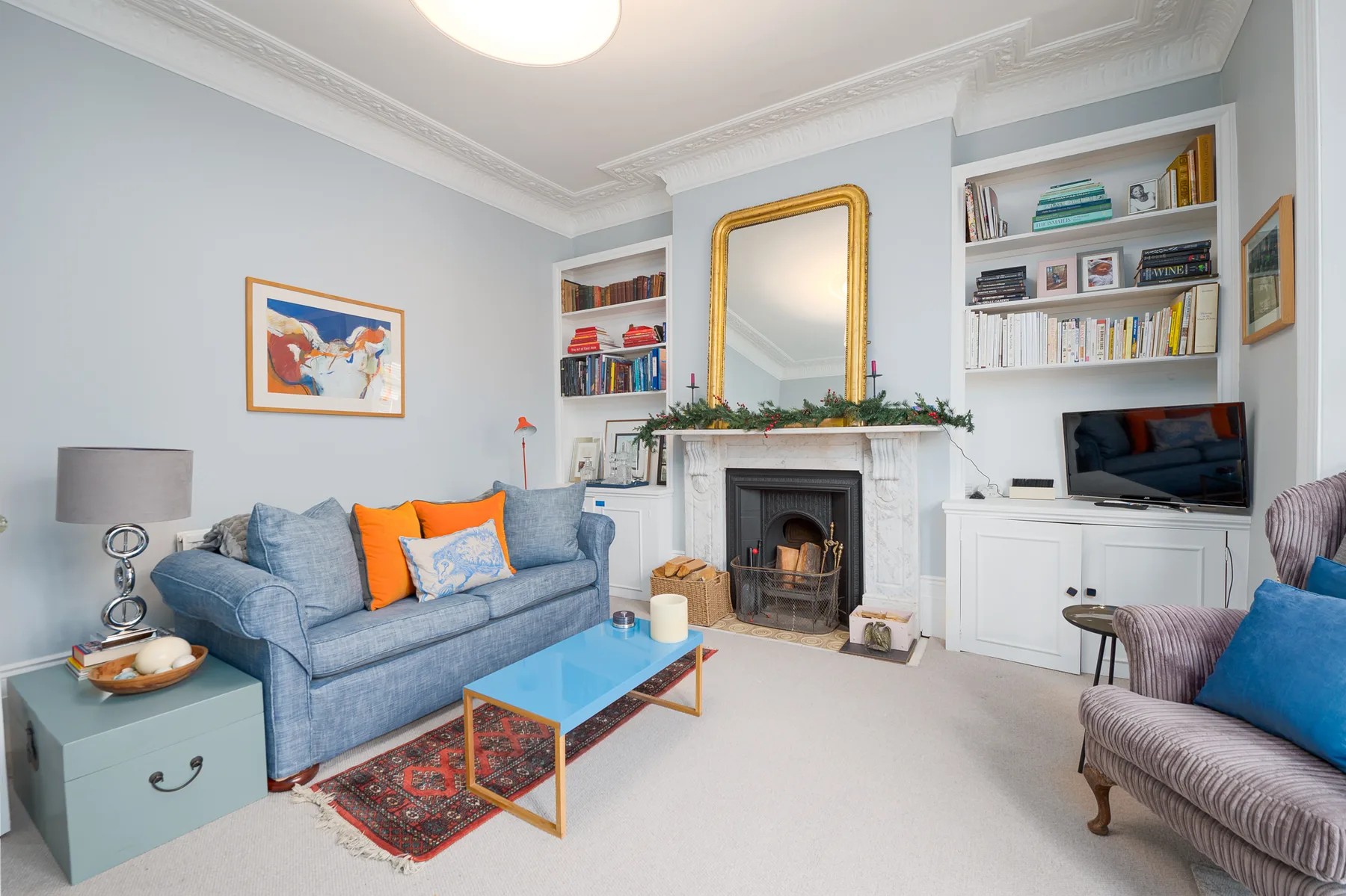 A living room with blue seating, a fireplace, and built-in shelves.