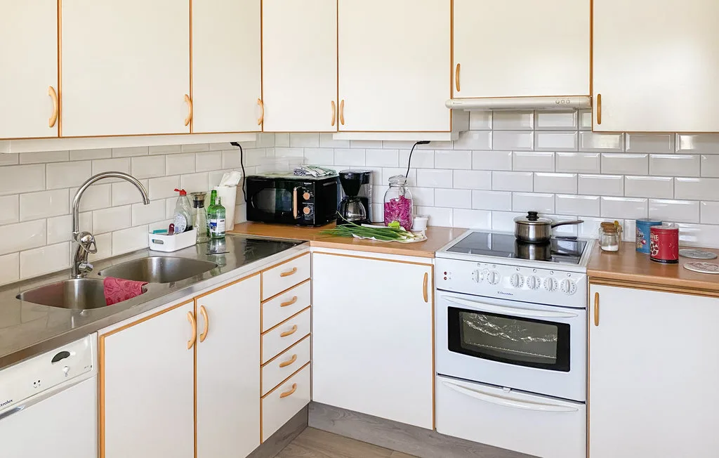 A bright kitchen with white cabinets, tiled backsplash, and a stove.