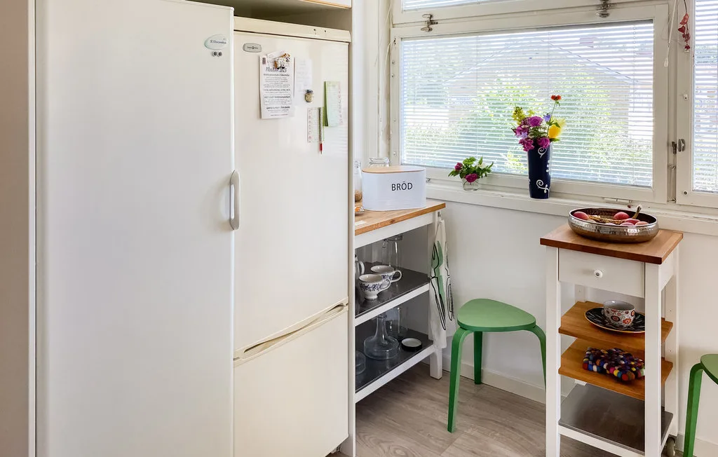 A bright kitchen with a refrigerator, counter, and green seating by the window.