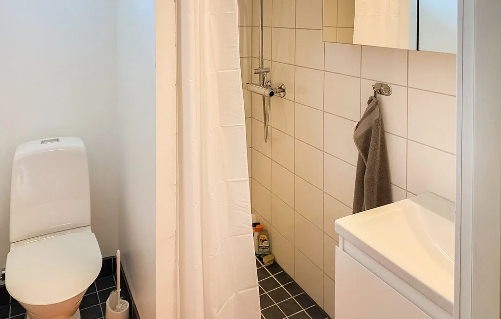 A tiled bathroom with a shower, toilet, and sink.