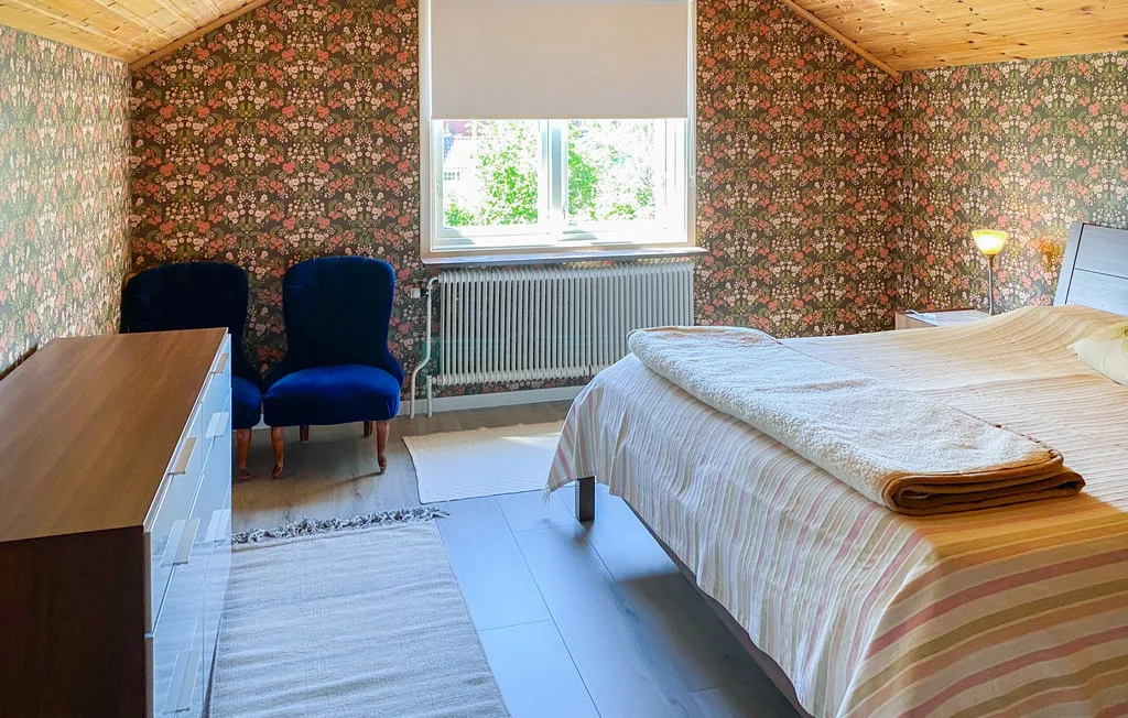 A bedroom with a bed, two chairs, and a window.