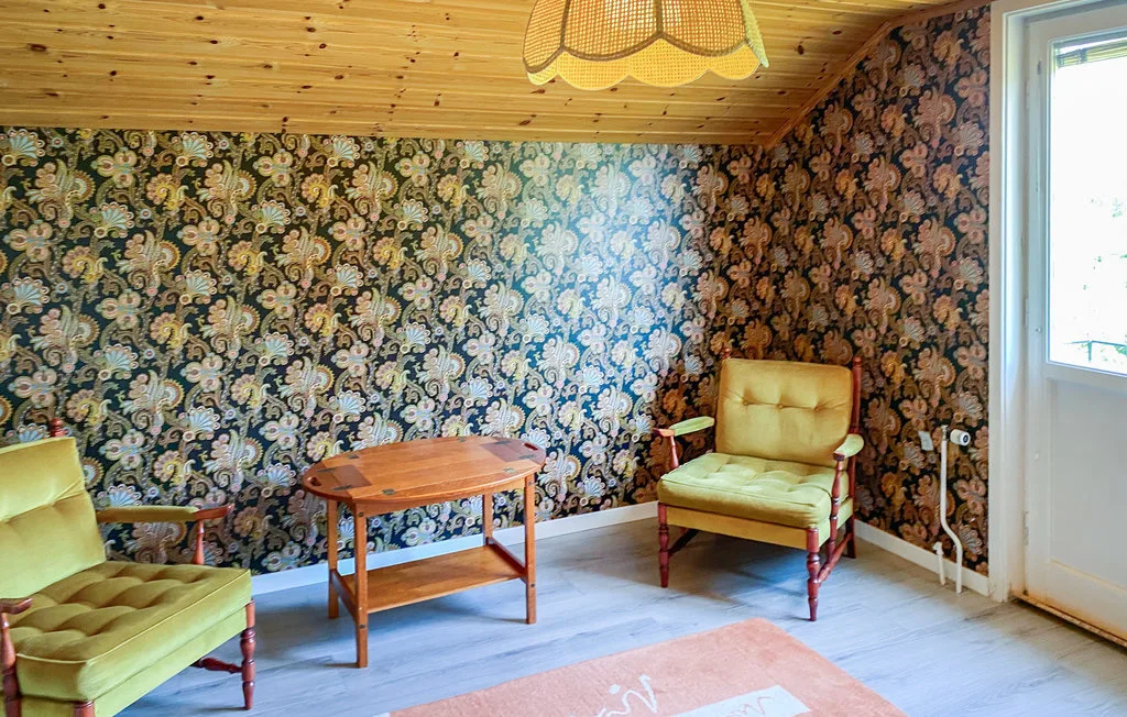 A sitting room with patterned wallpaper, cushioned seating, and a wooden coffee table.