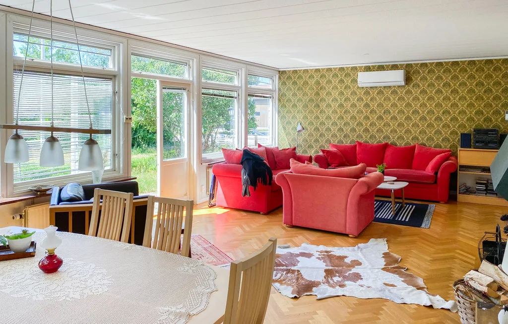 A living and dining room with red seating, a dining table, and large windows.