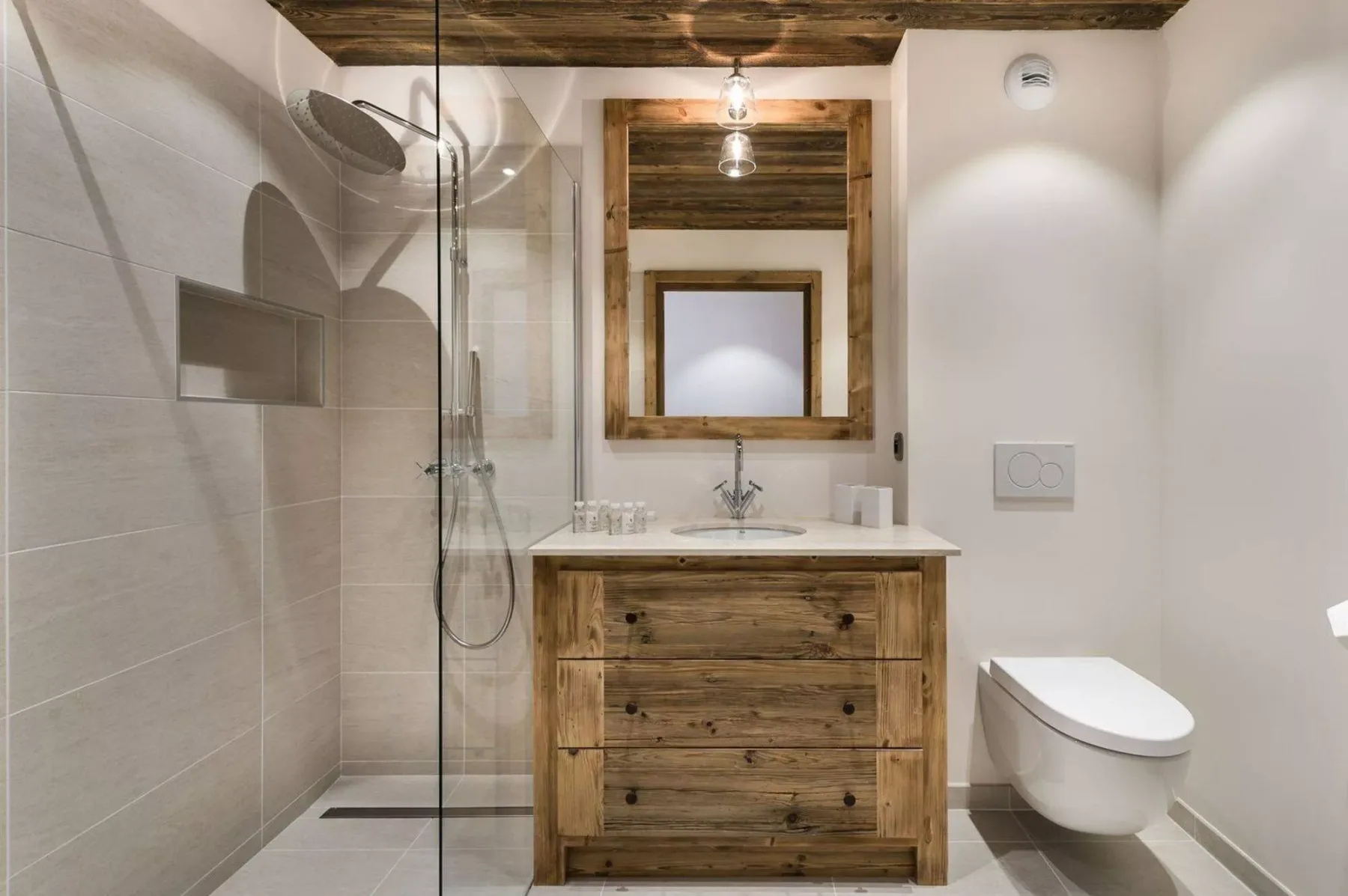A bathroom with a wood vanity, mirror, and glass shower.