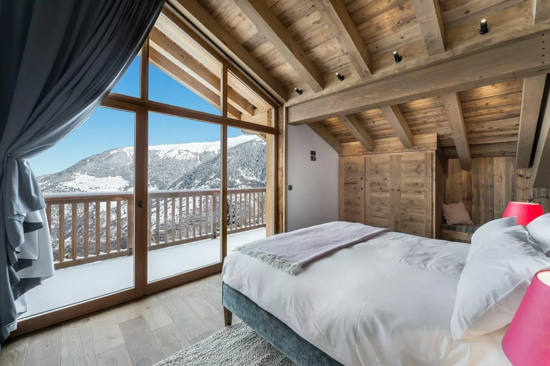 A bedroom with a large window overlooking a snowy mountain landscape.