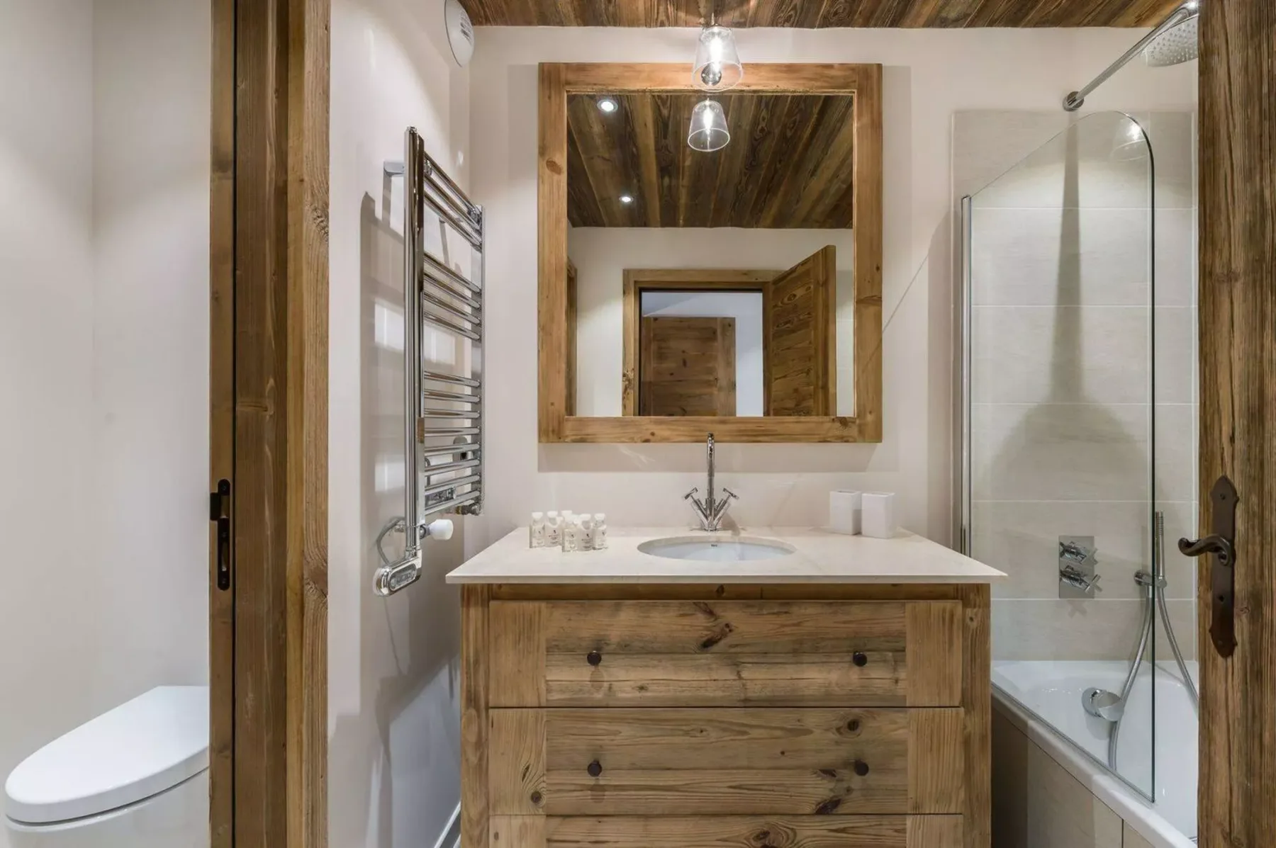 A bathroom vanity with a wood-framed mirror and a glass shower enclosure.