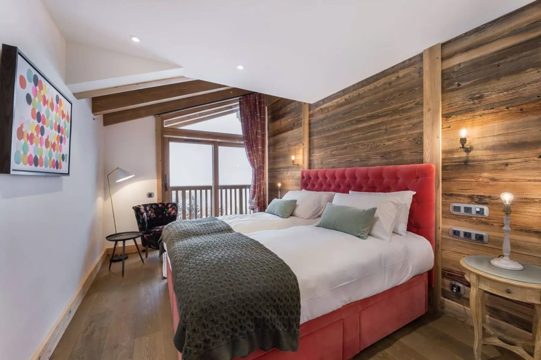 A bedroom with a bed against a wood-paneled wall and a window.