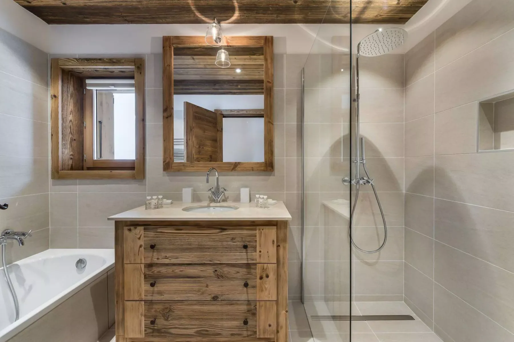 A bathroom with a wooden vanity, bathtub, and glass shower.