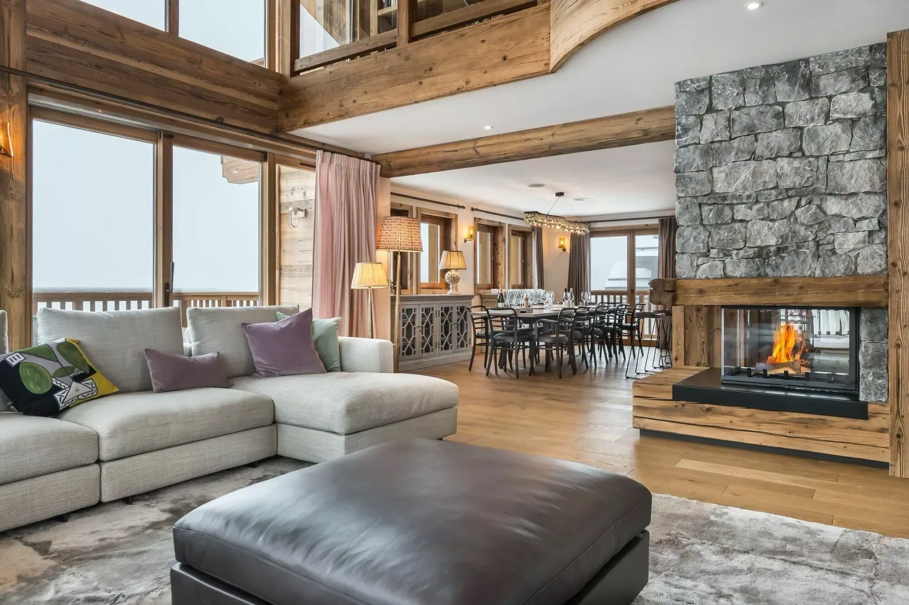 A spacious living and dining area features seating beside a stone fireplace.