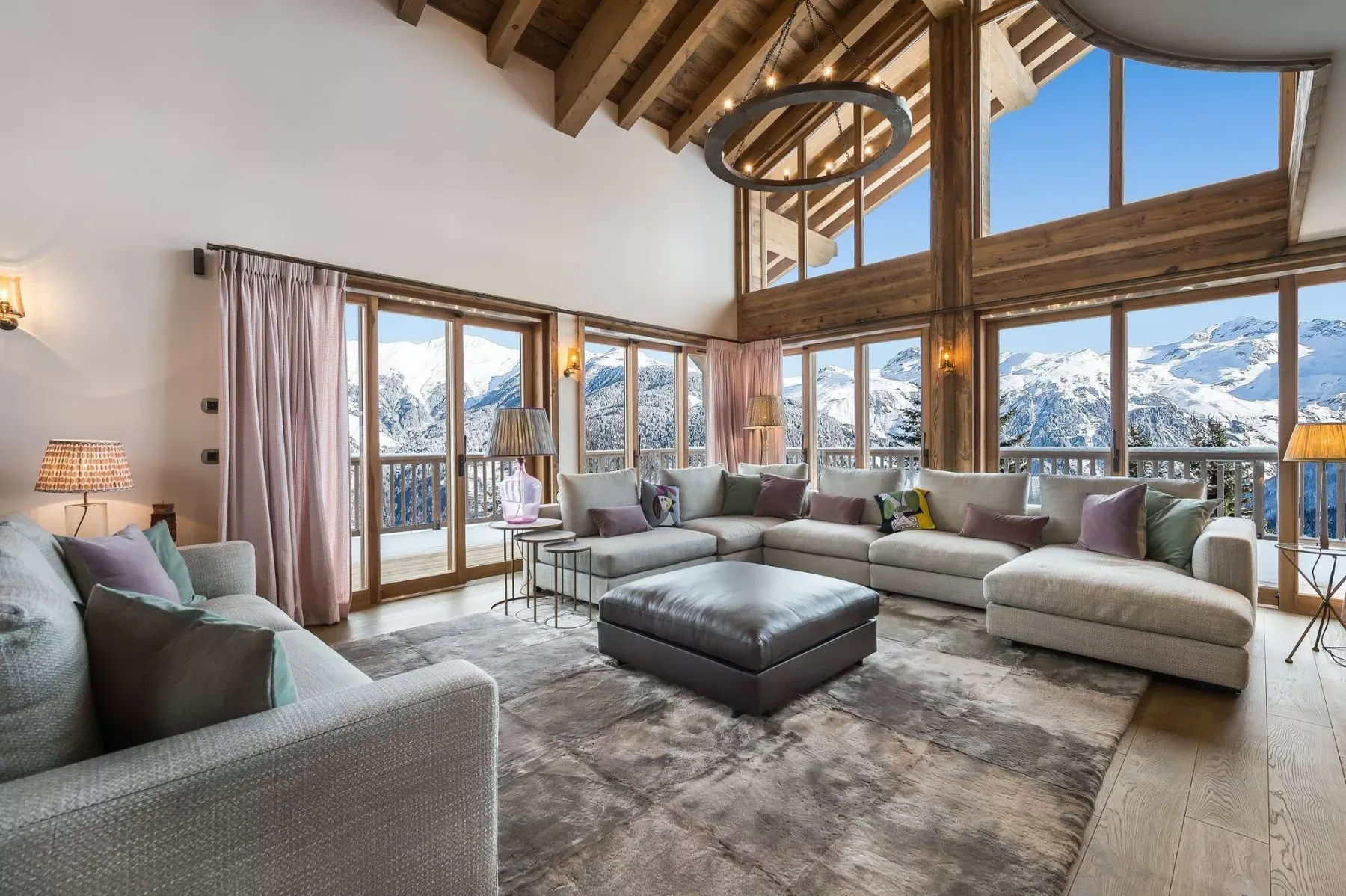 A spacious living room with seating and large windows overlooking a snowy mountain landscape.