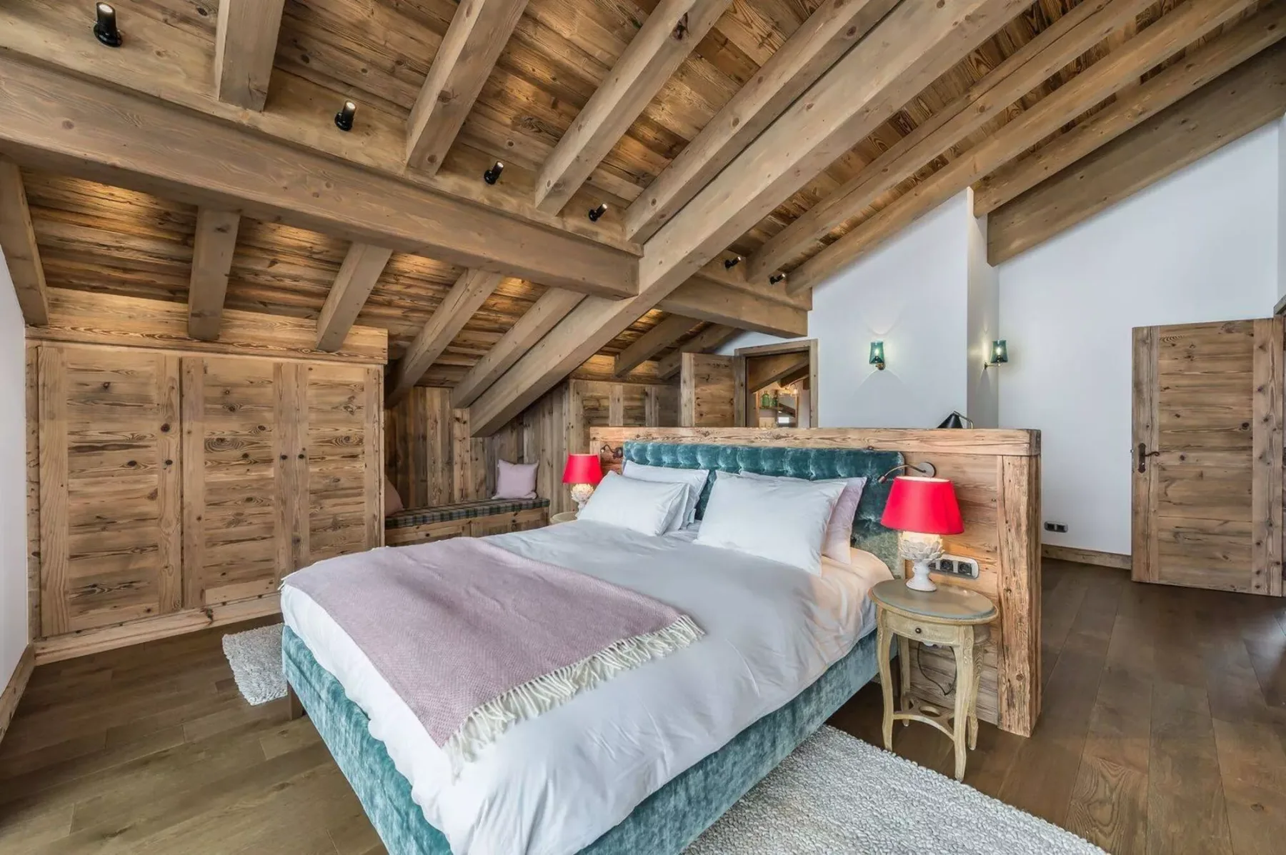 A bedroom with a bed beneath a sloped wooden ceiling.