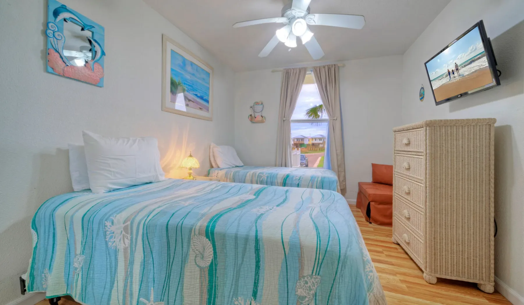 Un dormitorio con camas cubiertas con ropa de cama a rayas turquesas y una cómoda.