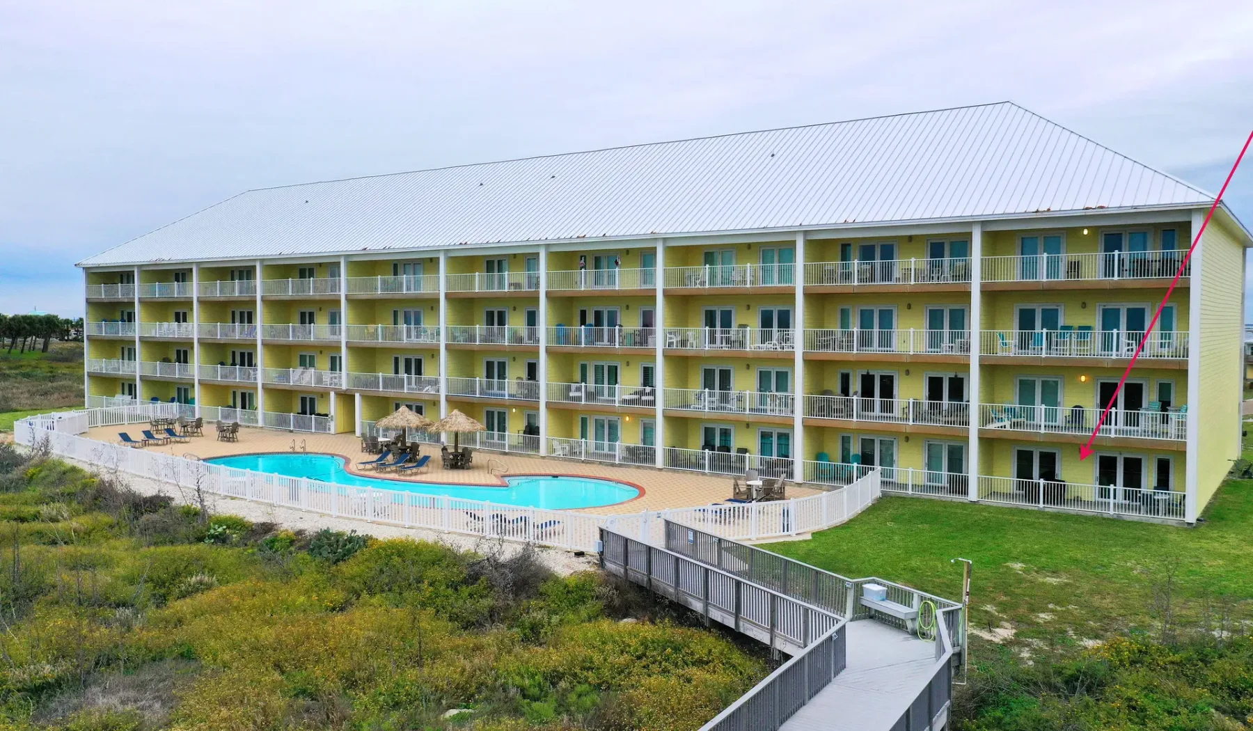 Un edificio de varios pisos da a una piscina y a una pasarela elevada.