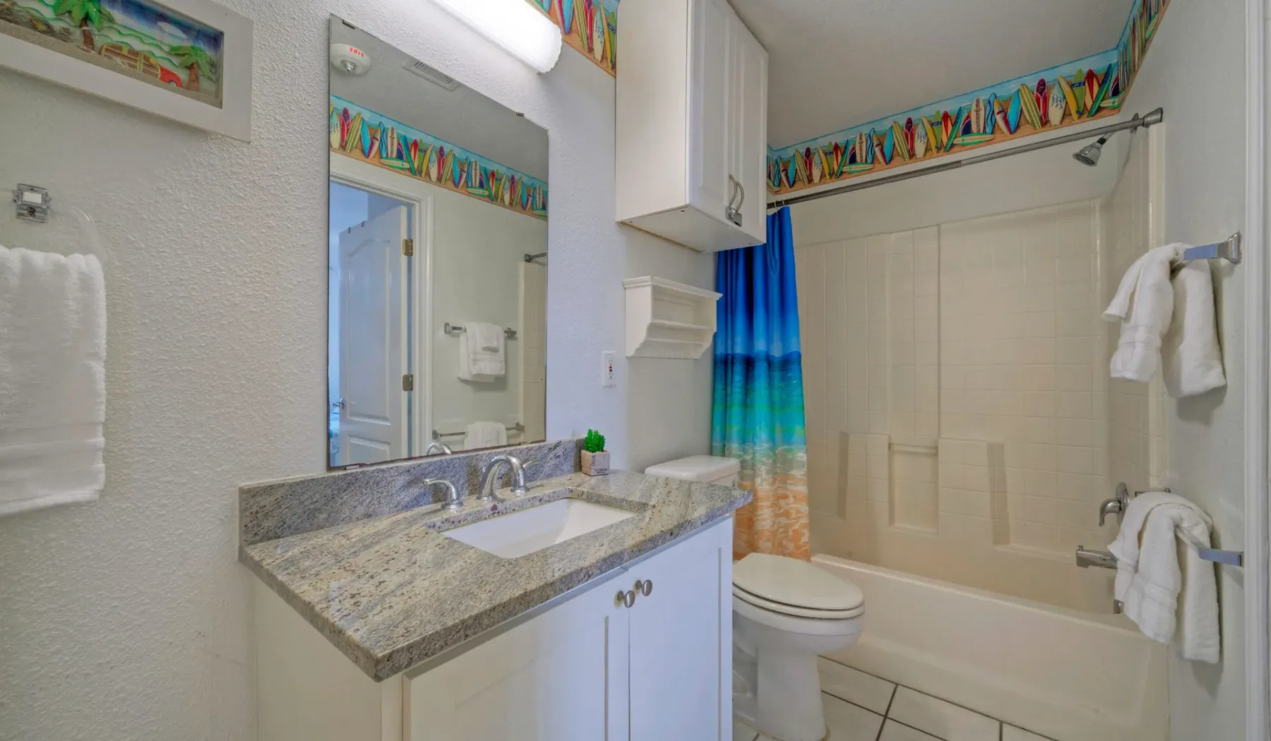 Un baño con lavabo, espejo, inodoro y bañera con cortina de ducha.