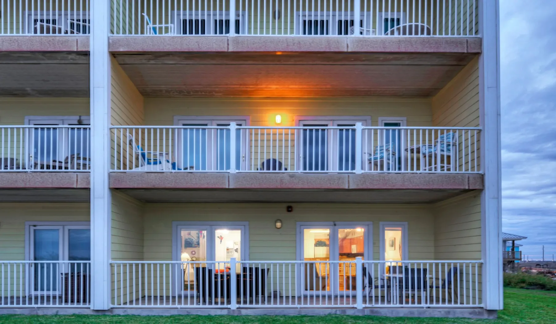 Fachada de un edificio de varias plantas con balcones superpuestos y ventanas iluminadas.