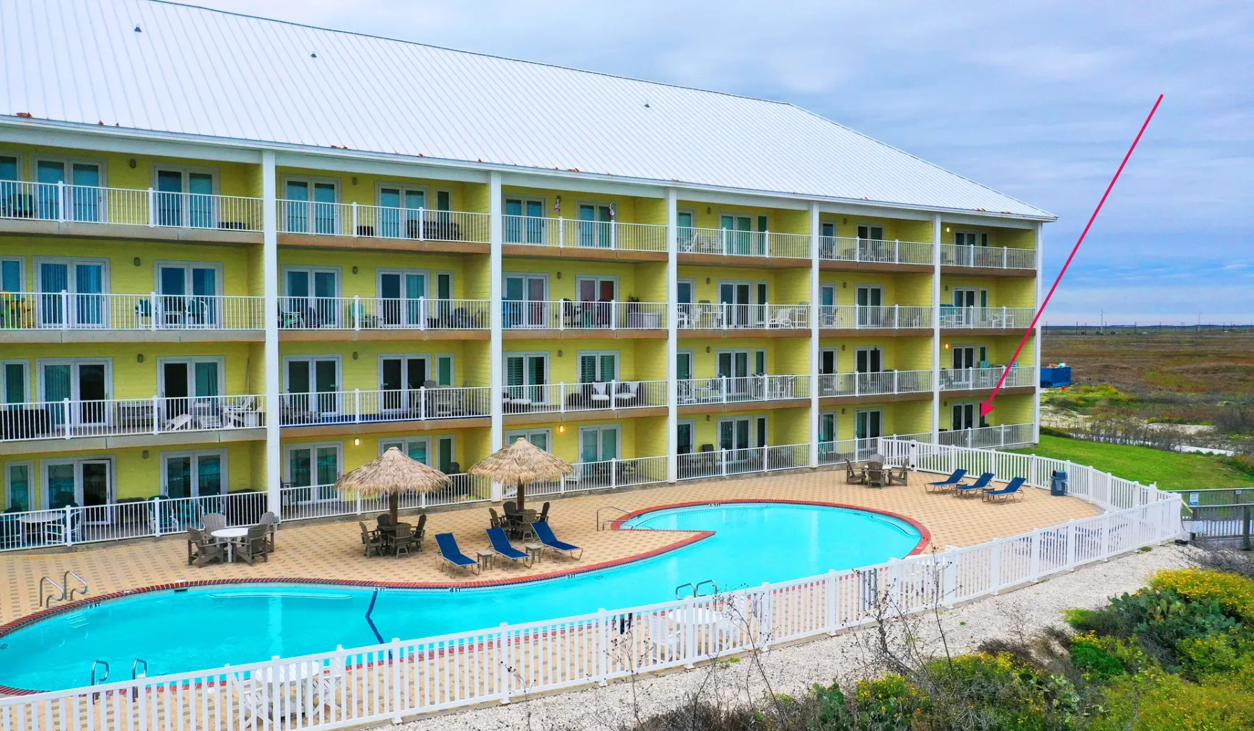 Un edificio de varios pisos da a una piscina al aire libre y una terraza.