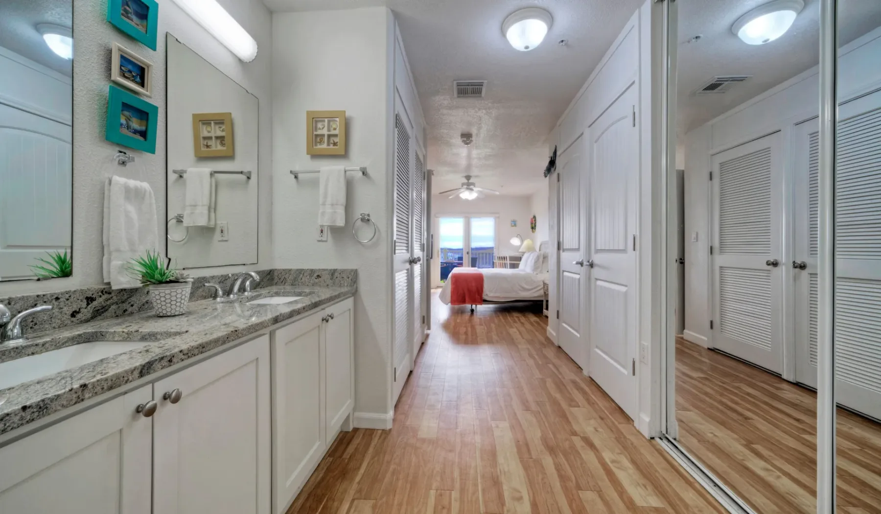 Un tocador de baño luminoso da a un pasillo que conduce a un dormitorio.