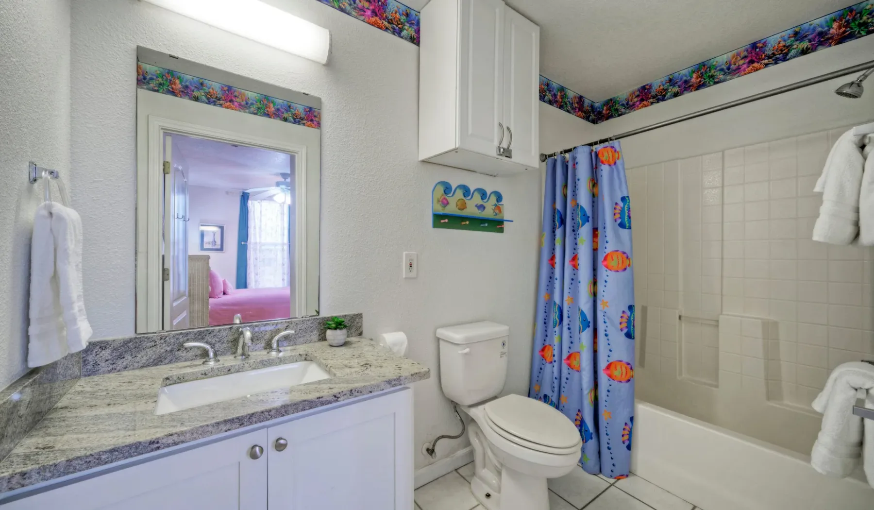 Un baño con lavabo, inodoro y bañera detrás de una cortina de ducha colorida.