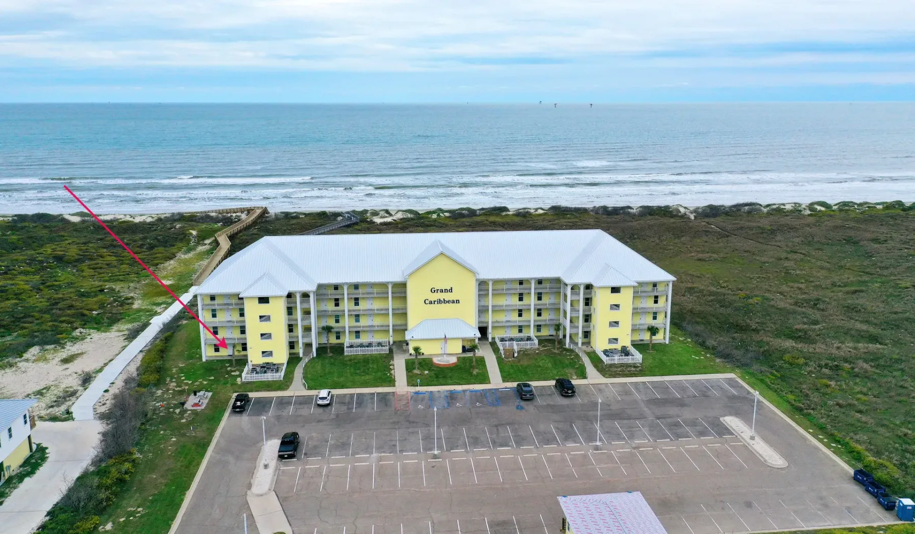 Un edificio de apartamentos frente al mar, con un estacionamiento delante.