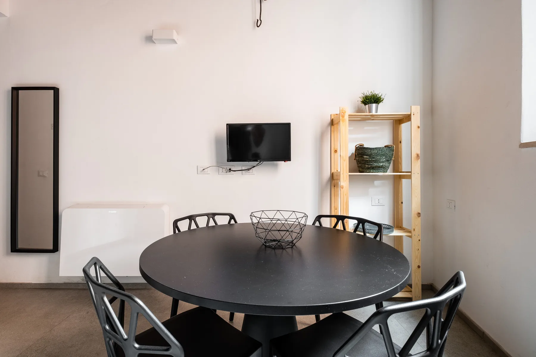 Comedor con una mesa redonda, sillas y un televisor montado en la pared.