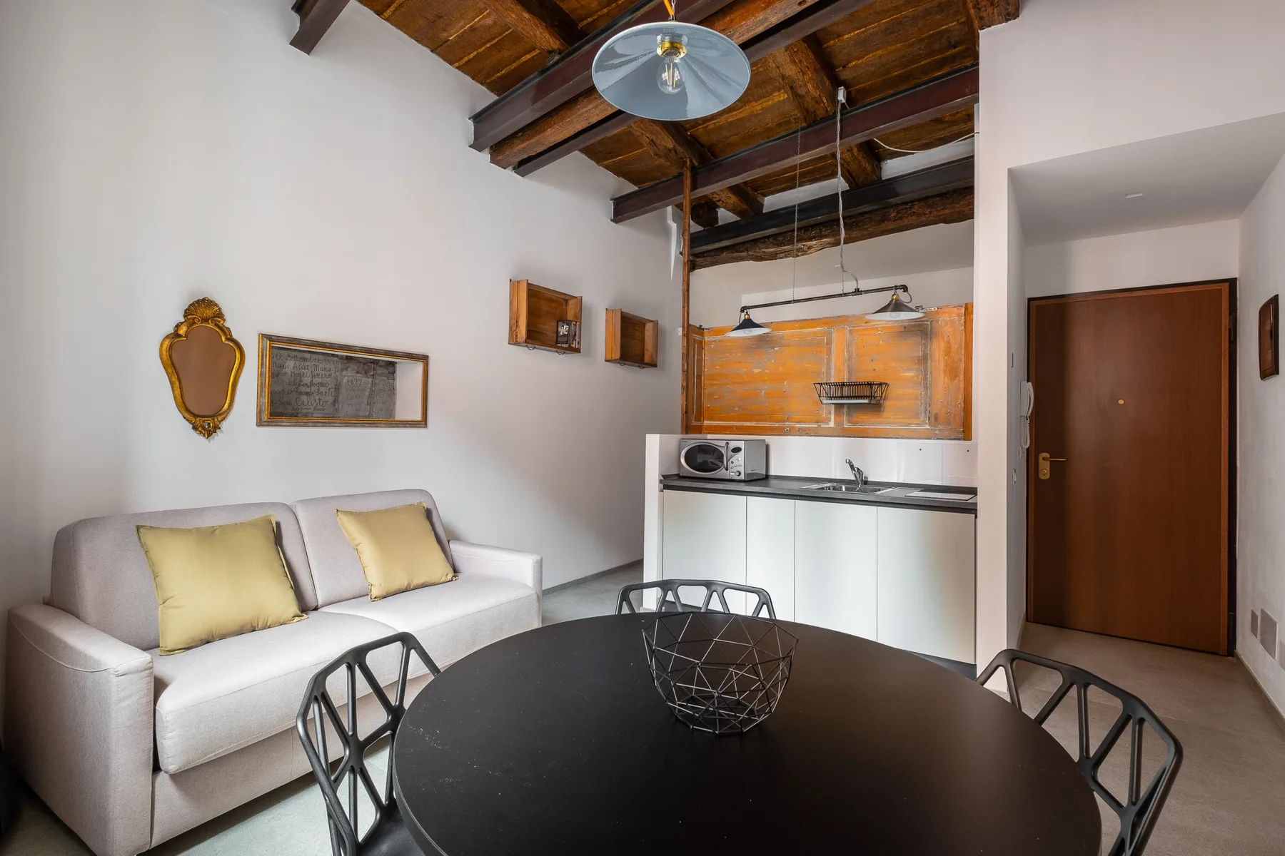Una pequeña sala de estar y comedor con un sofá blanco y una mesa redonda oscura.