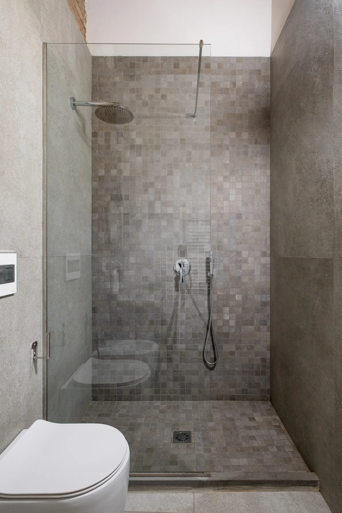 Un baño con azulejos, una ducha de vidrio y un inodoro al lado.