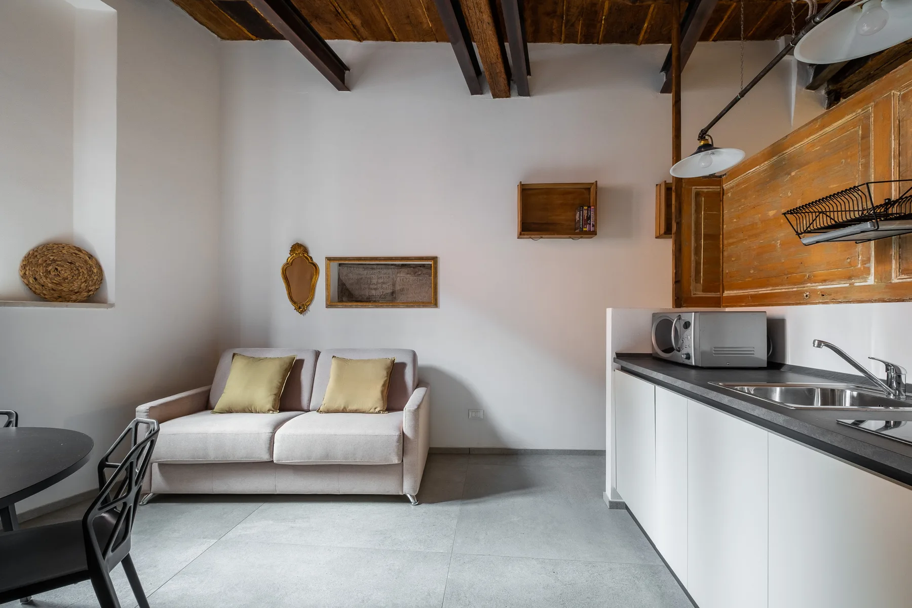 Una pequeña sala de estar con un sofá junto a una cocina pequeña.