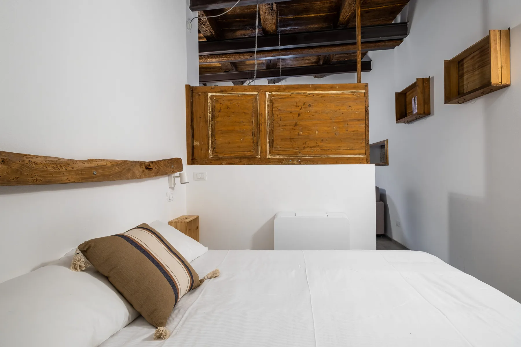 Un dormitorio con una cama blanca bajo vigas de madera.