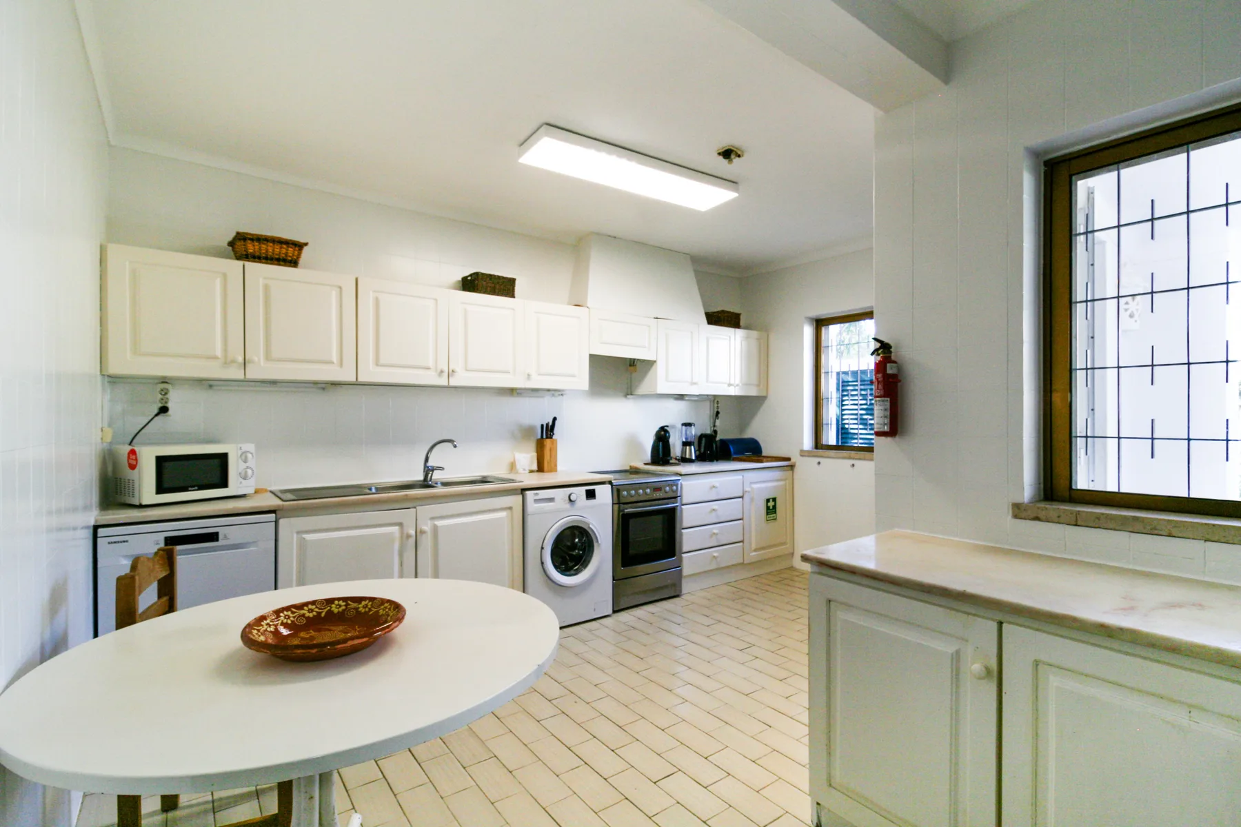 Una cocina luminosa con una mesa redonda, armarios y electrodomésticos.