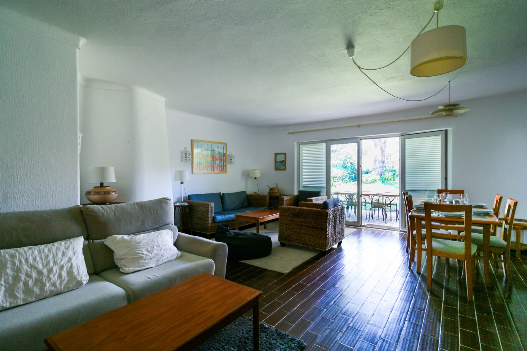 Sala de estar con asientos y una mesa de comedor junto a grandes puertas de vidrio.
