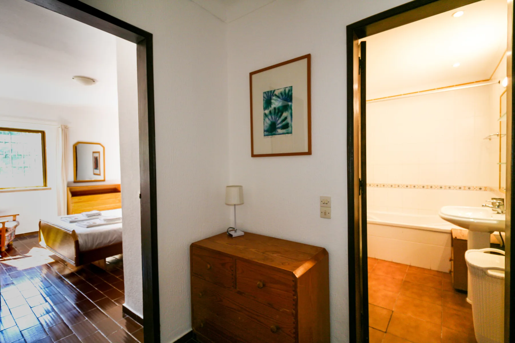 Un pasillo conecta un dormitorio con un baño bien iluminado.