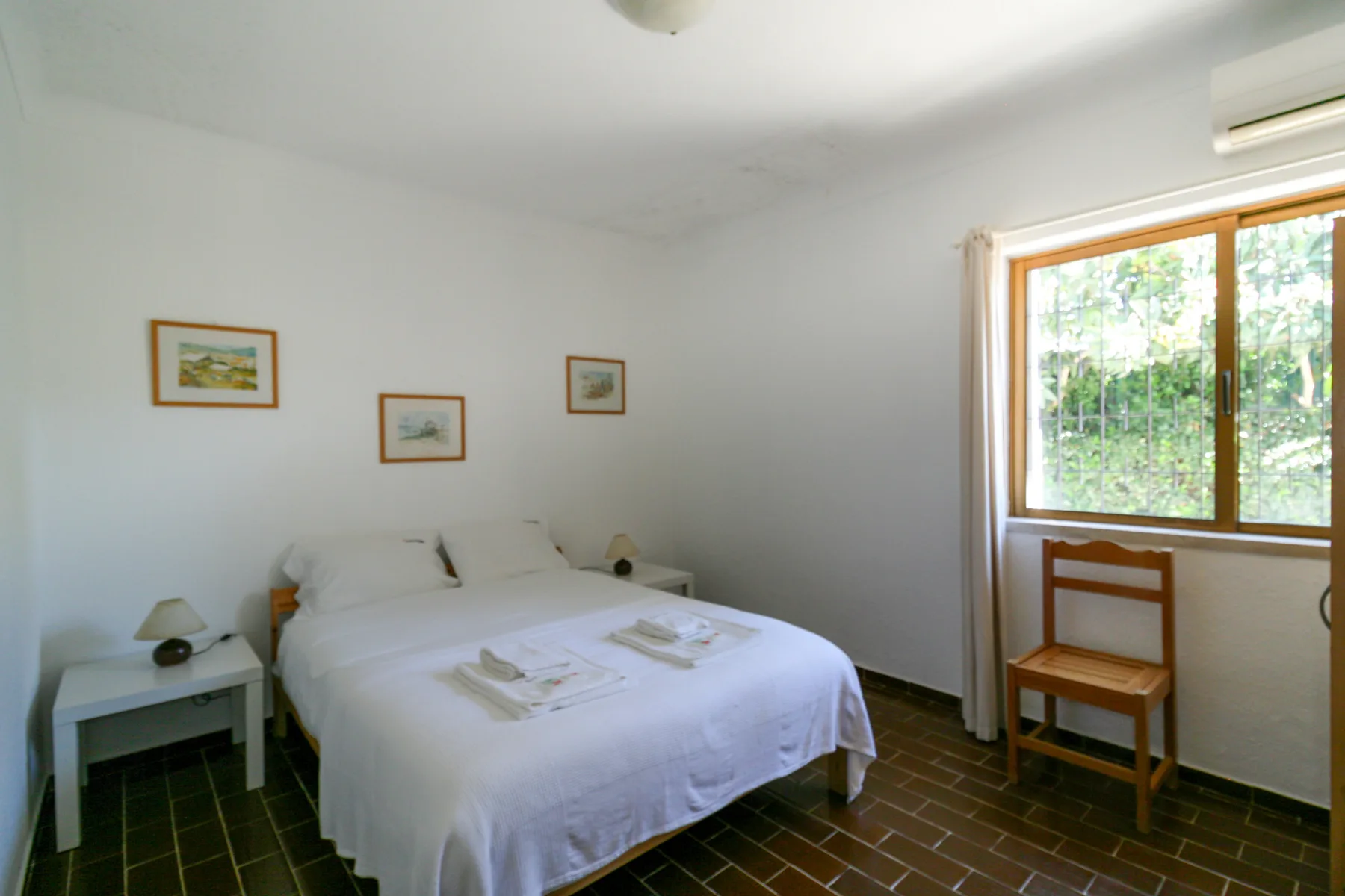 Un dormitorio con una cama bien arreglada y una ventana amplia.