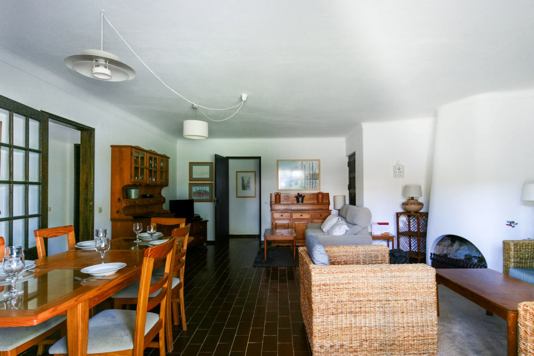 Una sala de estar y comedor con asientos de madera, un mueble y una chimenea.