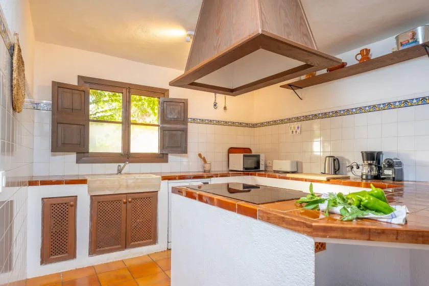 A tiled kitchen with a central island and a window above the sink.