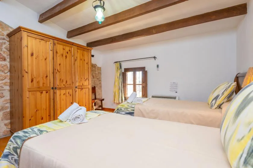 A bedroom with two beds, a wooden wardrobe, and exposed ceiling beams.